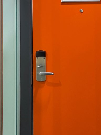 An orange door with a handle which resembles a face