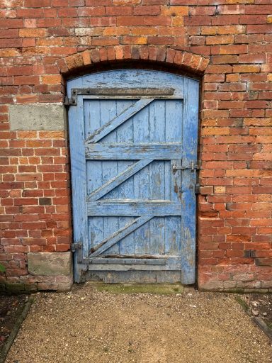 An aging blue wooden door set in a brick wall